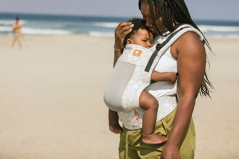 A child being carried in a baby carrier in summer.