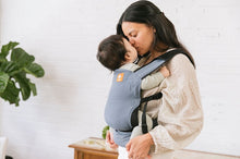 Mother and child giving each other a kiss while using the lightweight Lite Travel Carrier Slate from Tula.