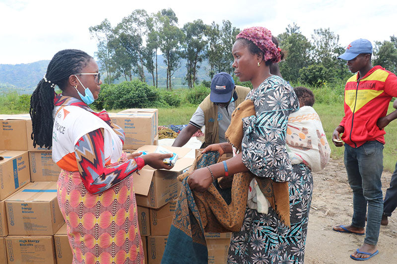 In the Democratic Republic of the Congo, a woman with her baby in a carrier on her back receives emergency supplies from a World Vision emergency staff member.