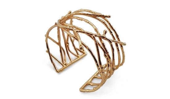 An adjustable cuff bracelet with twig designs in brass finish.