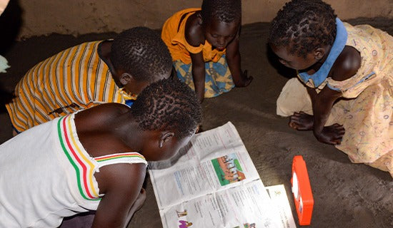 Four children huddle on the floor over a large, colourful worksheet.