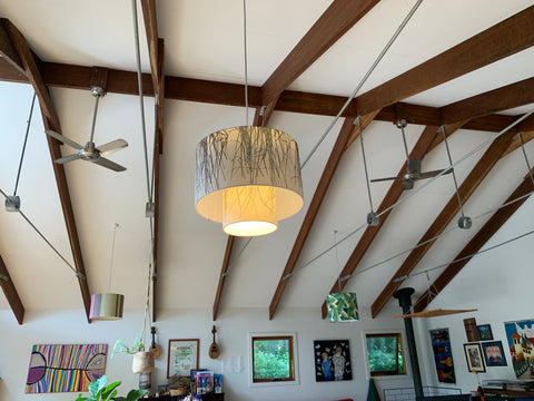 tiered lampshade lit up in living room with raked ceiling and exposed beams