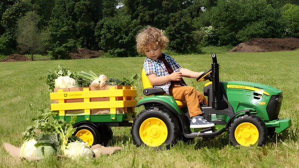 kid on the tractor full of vegetables outside the field to play