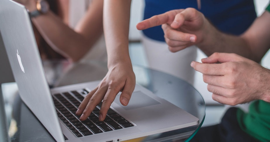 Das Foto zeigt einen Laptop, auf den zwei Personen zeigen und etwas besprechen. Im Beitrag zeigen wir dir, wie du den richtigen Domainregistrar auswählst.