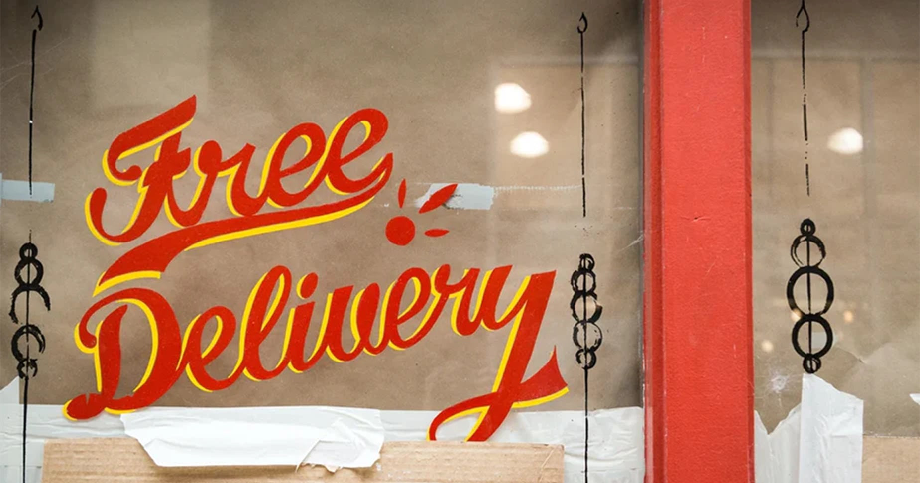 Zu sehen ist ein rot-gelber "Free Delivery"-Schriftzug auf einer Wand.