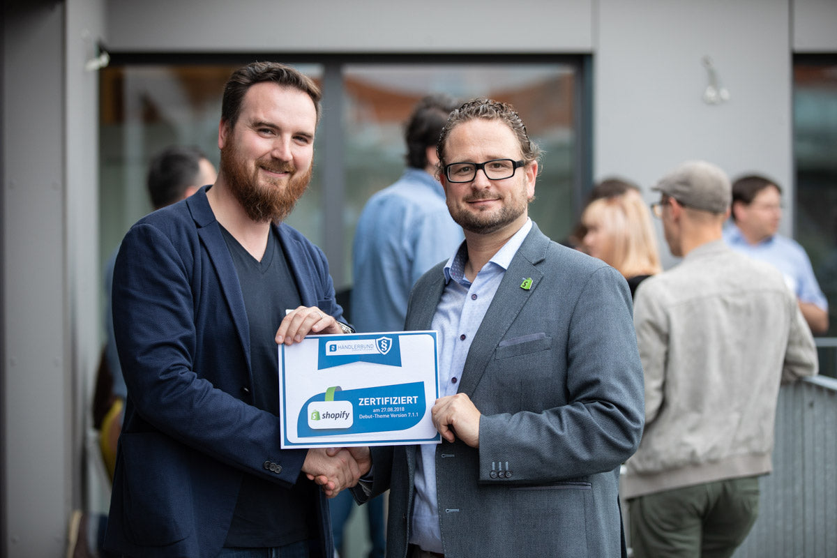 Händlerbund COO Tim Arlt (links) übergibt das Zertifikat an Hagen Meischner von Shopify.