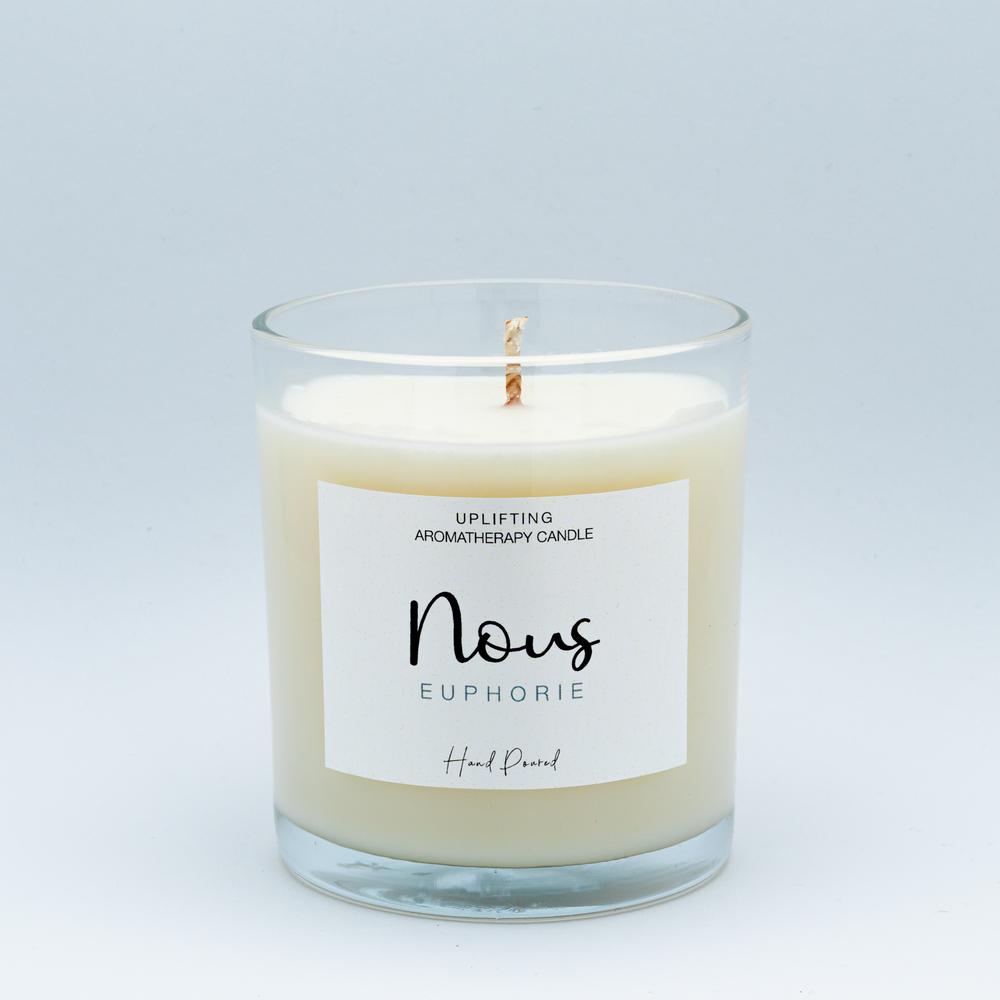Eine weiße Kerze vor hellem Hintergrund der Marke nous, die Kerzen online verkauft