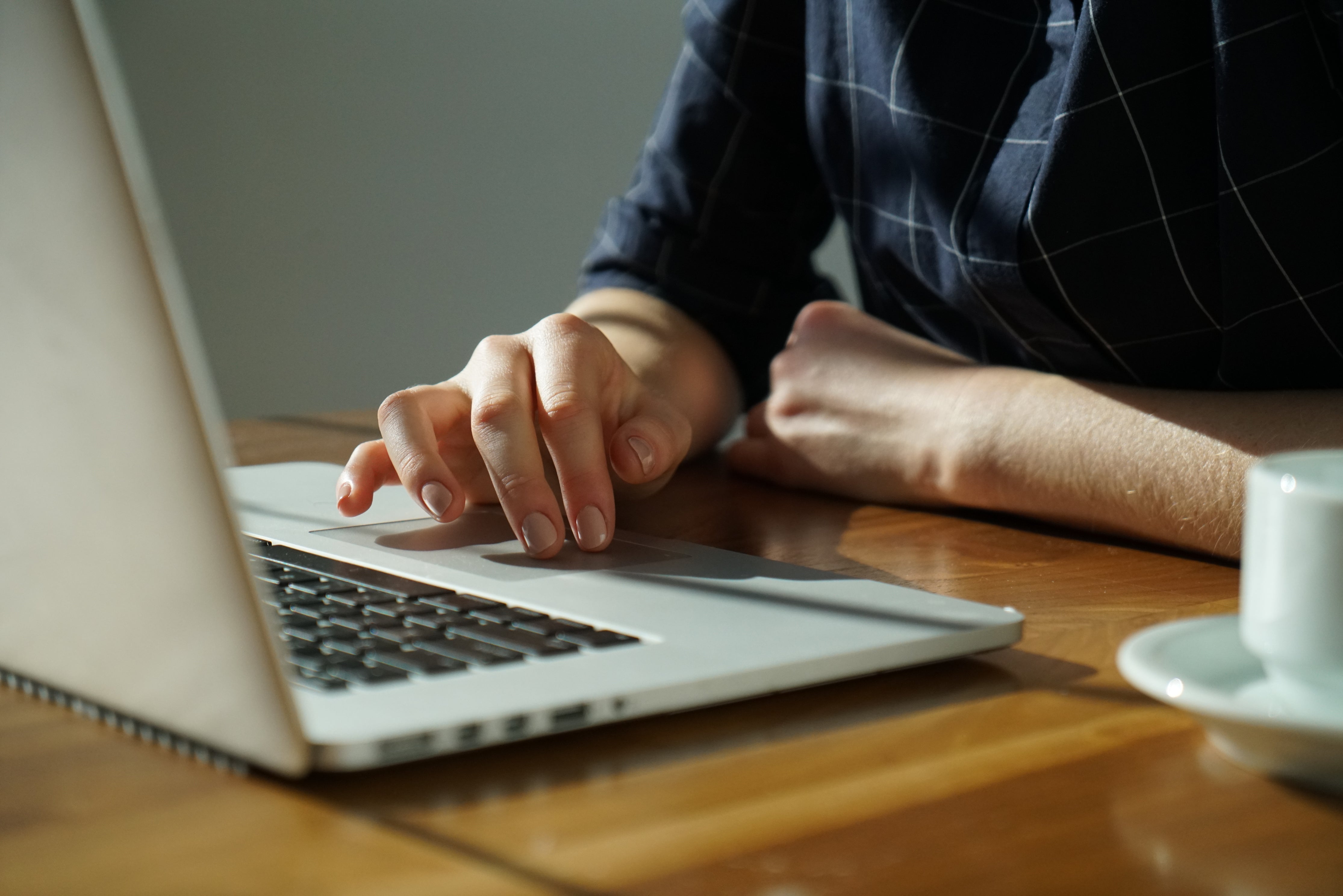 Blick auf einen Schreibtisch an dem eine Person vor einem aufgeklappten Laptop sitzt und arbeitet. Daneben steht eine Kaffeetasse. Wir zeigen dir, wie du das D2C-Modell in der Praxis umsetzen kannst!