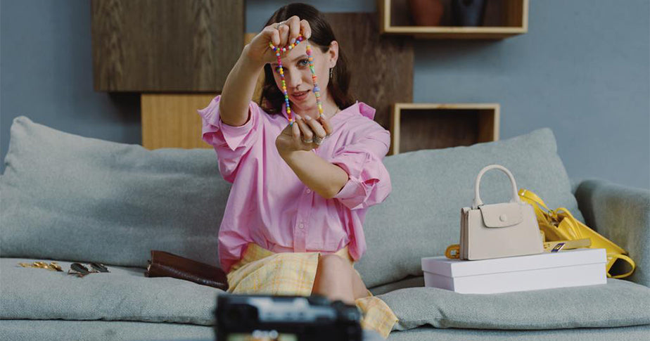 Das Auge shoppt beim Visuellen Marketing mit, hier eine Frau in rosabluse die eine bunte Kette in die Kamera hält