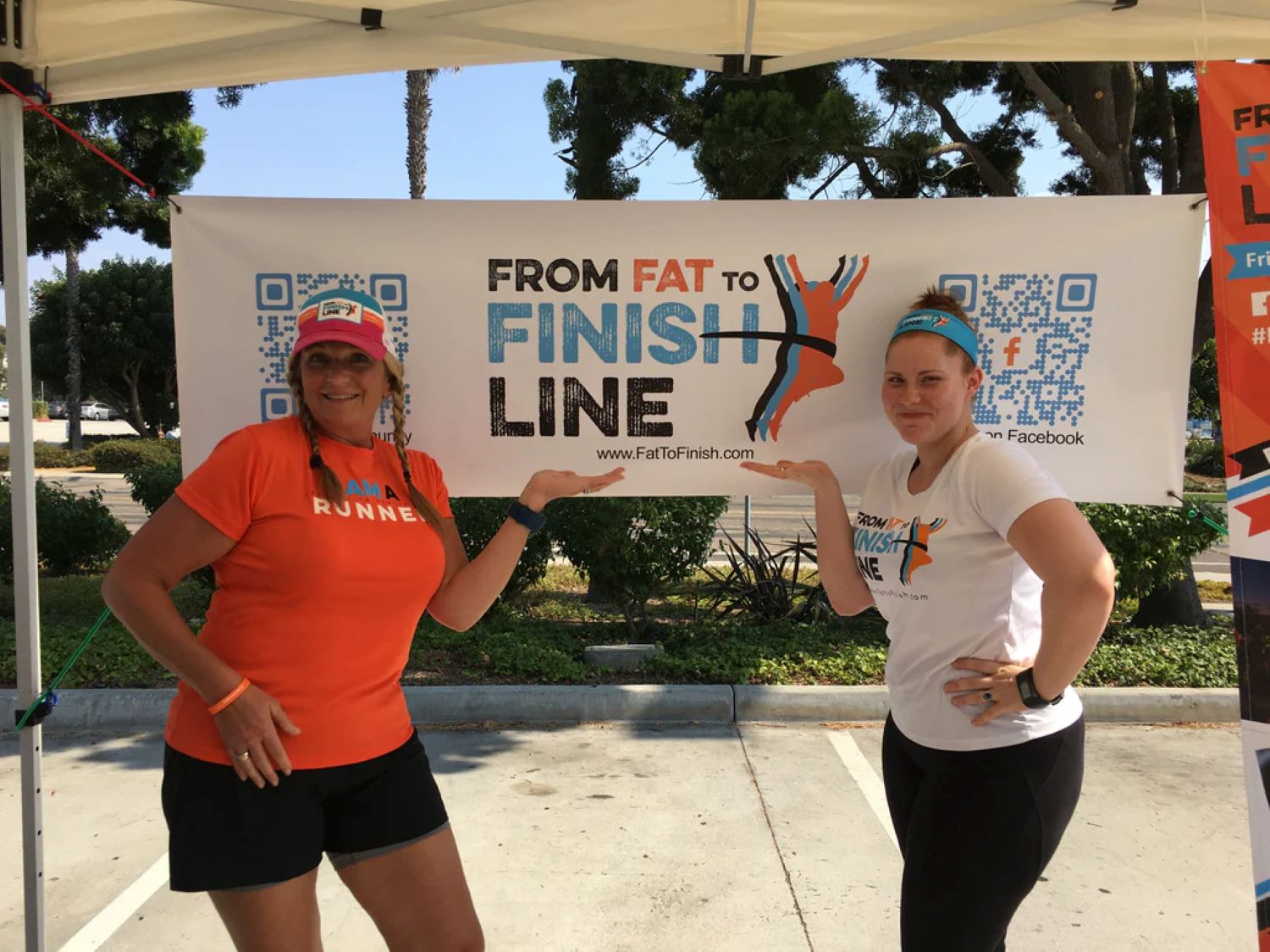 Gezeigt sind zwei Frauen in Sportkleidung, die vor einem weißen Banner stehen. Auf dem Banner steht "from fat to finish line."