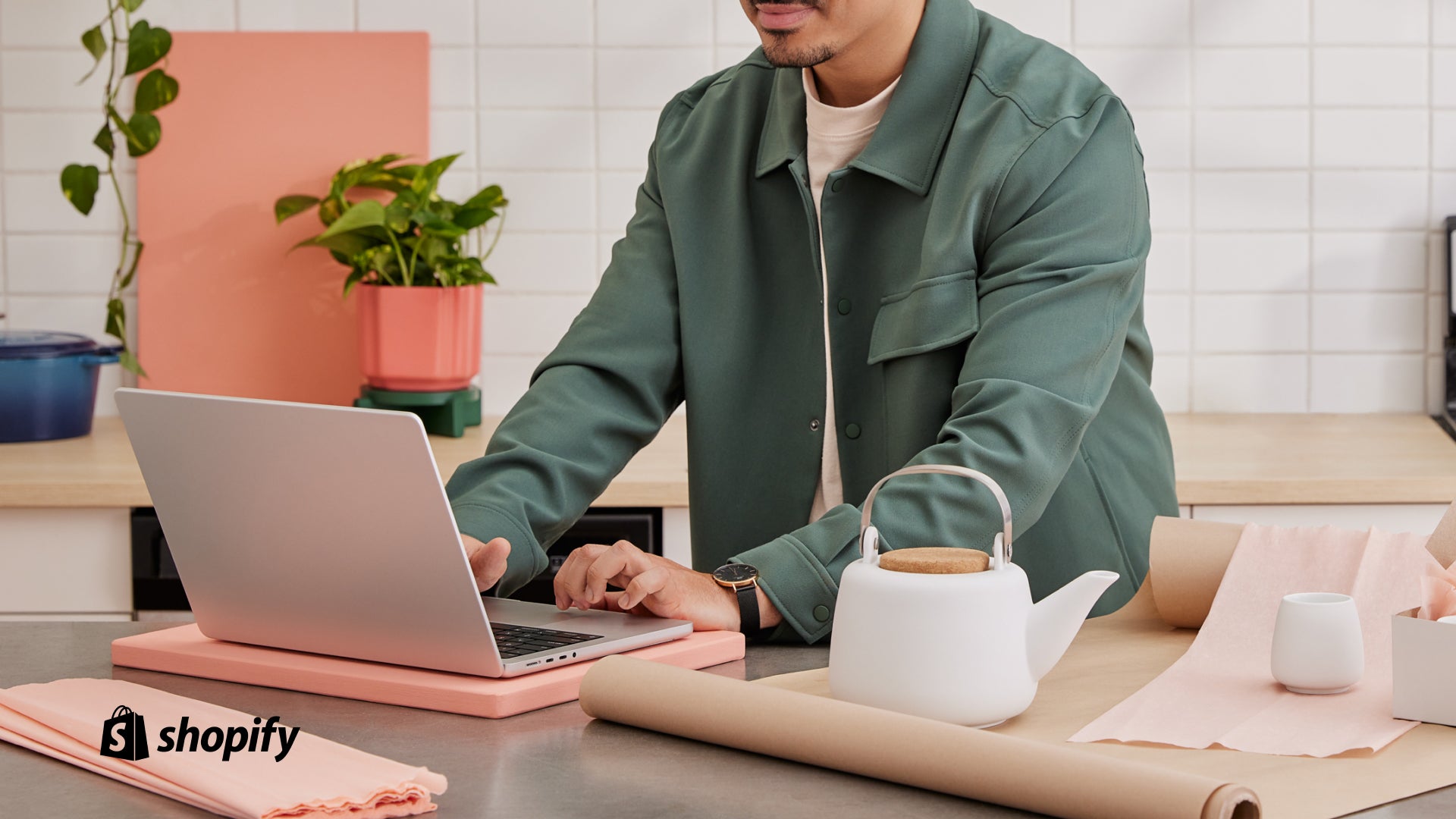 Bild eines Mannes an einer Theke, umgeben von Einrichtungsgegenständen, während er an einem Laptop arbeitet