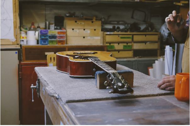 Für einen neu eröffneten Secondhandladen wird eine Gitarre in einer Werkstatt aufbereitet.