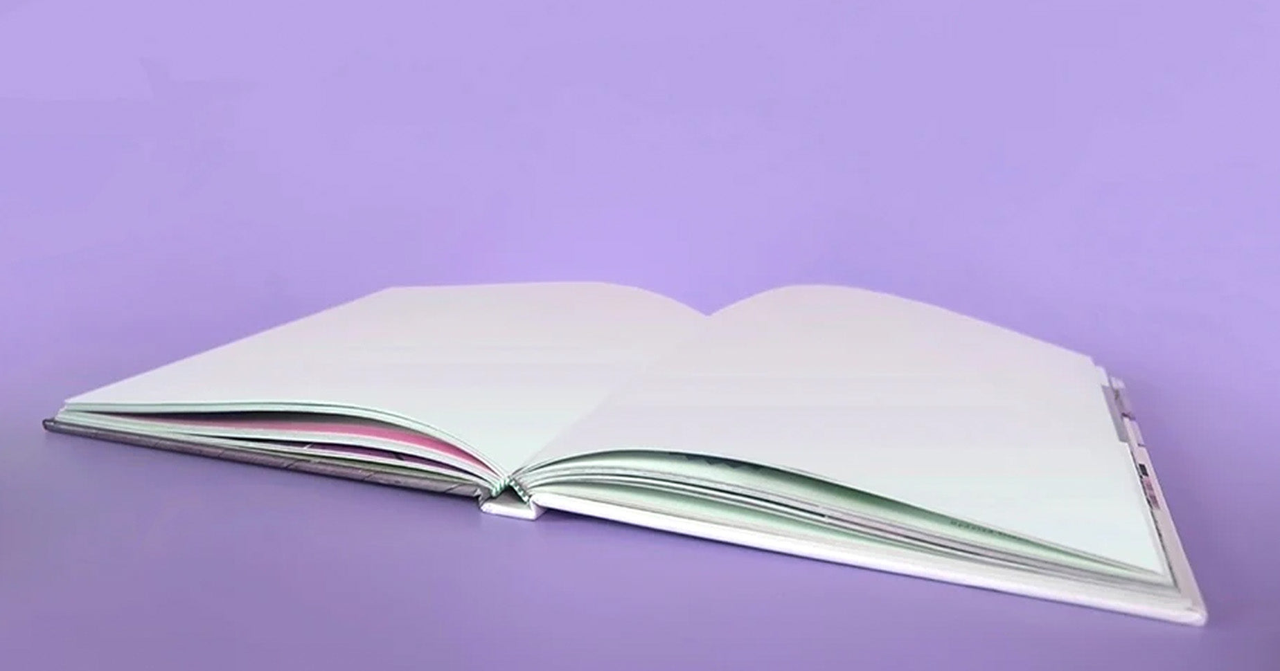 Ein aufgeklapptes Notizbuch vor einem lila Hintergrund.
