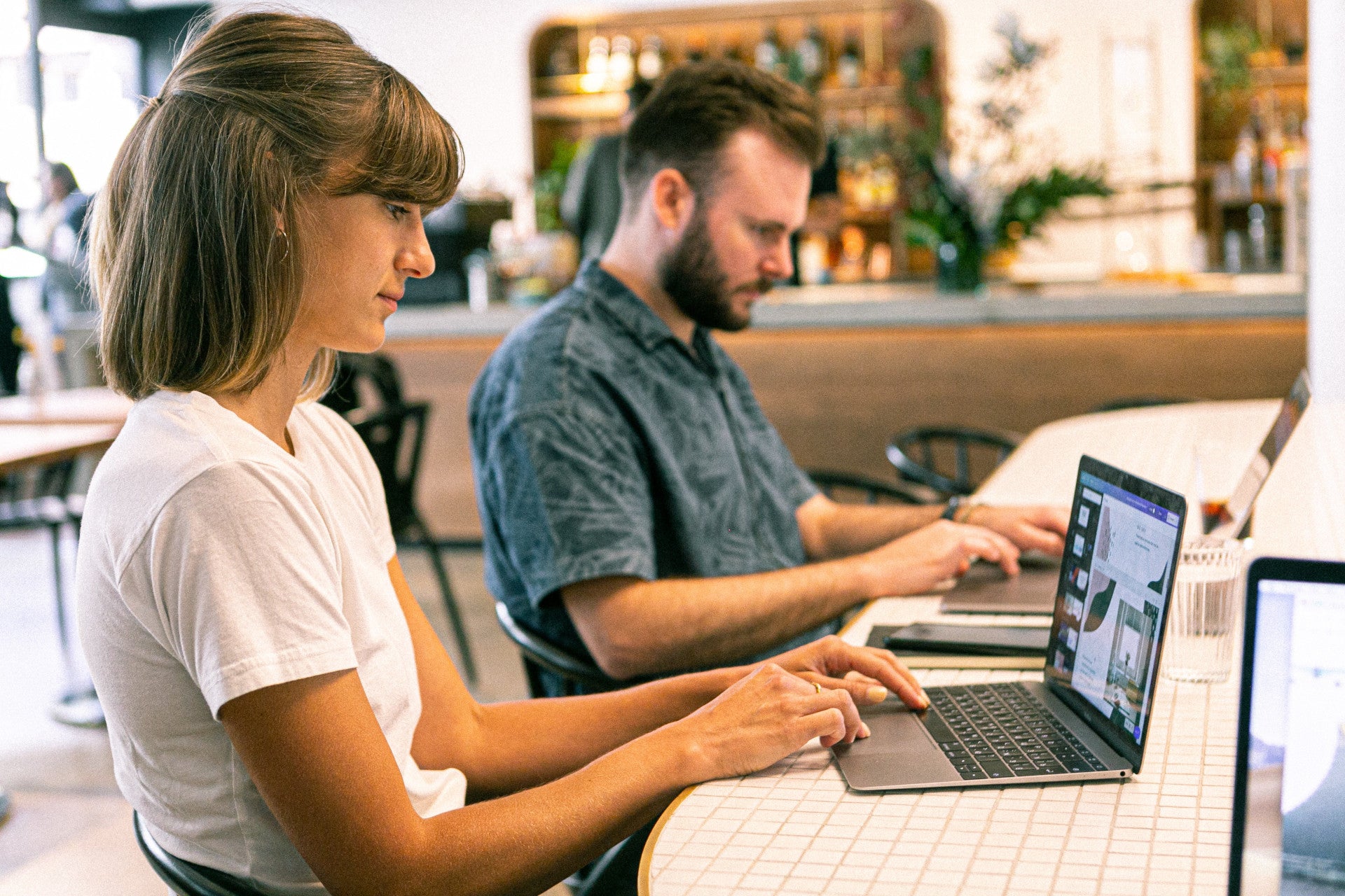 Blick in eine Café. Am Tisch im Vordergrund sitzen eine junge Frau und ein junger Mann jeweils vor einem Laptop und arbeiten. Erfahre mehr zu den Grundlagen des Affiliate-Marketings im Beitrag!