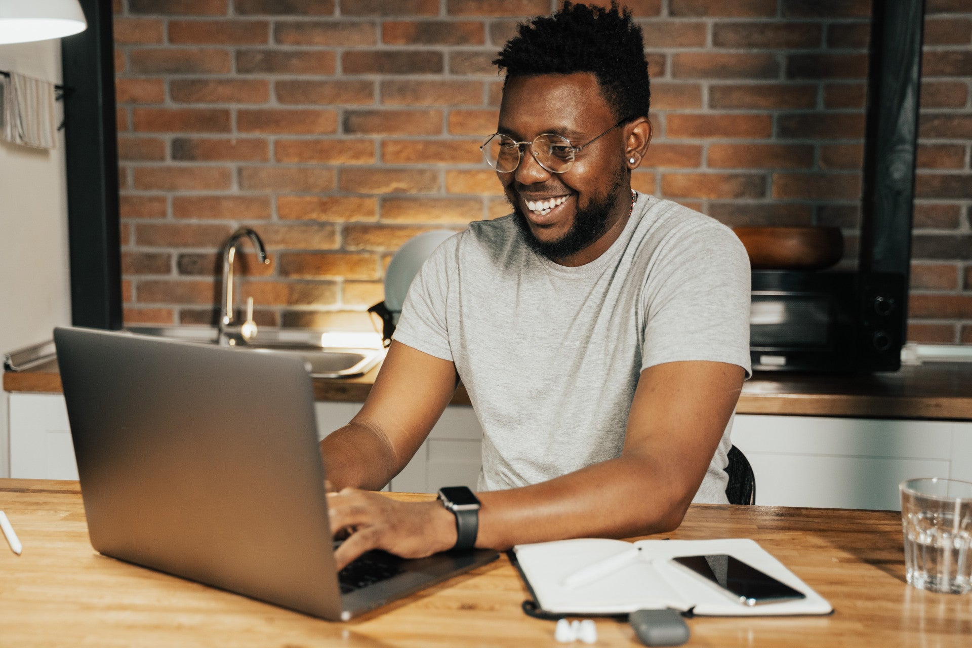 Blick in ein Büro an dem ein junger schwarzer Mann an einem Schreibtisch vor einem Laptop sitzt und arbeitet. Wir zeigen dir Schritt für Schritt, wie du mit Affiliate-Marketing starten kannst.