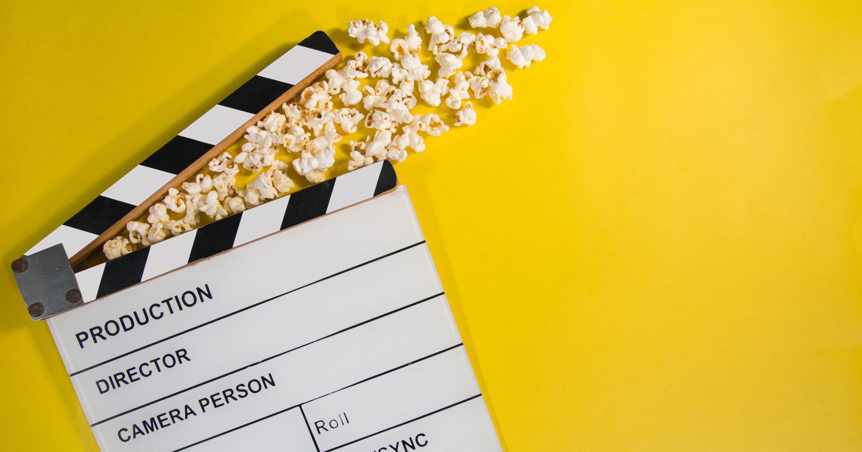 Auf einem gelben Untergrund liegt eine Filmklappe mit Popcorn zum Start des Drehs für After-Sales-Videos
