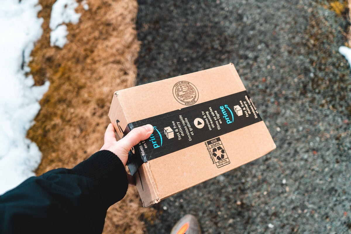 Das Foto zeigt eine Person, die ein Paket von Amazon in der Hand hält. Wir zeigen dir im Beitrag, welche Möglichkeiten du hast, um auf Amazon zu verkaufen.