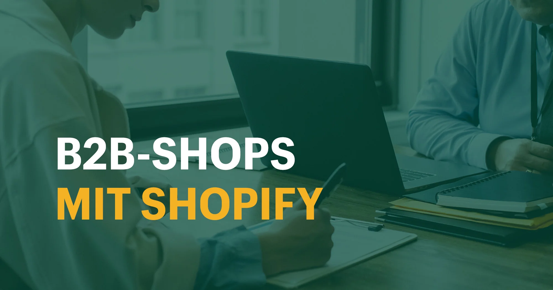 Zu sehen ist der Text "B2B-Shops mit Shopify" auf einem Bild mit zwei Personen, die an einem Schreibtisch arbeiten.