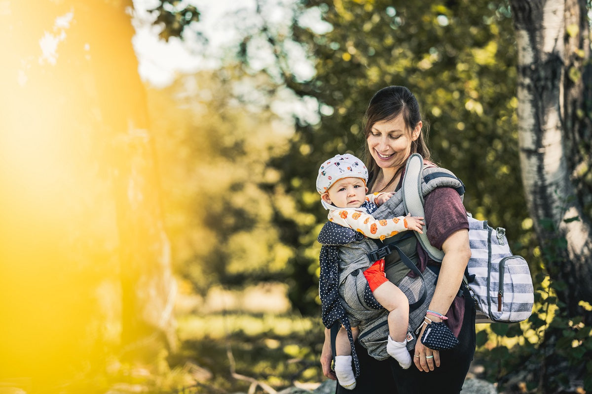 Das Foto zeigt eine Frau, die ein Baby in einem Babytuch trägt.