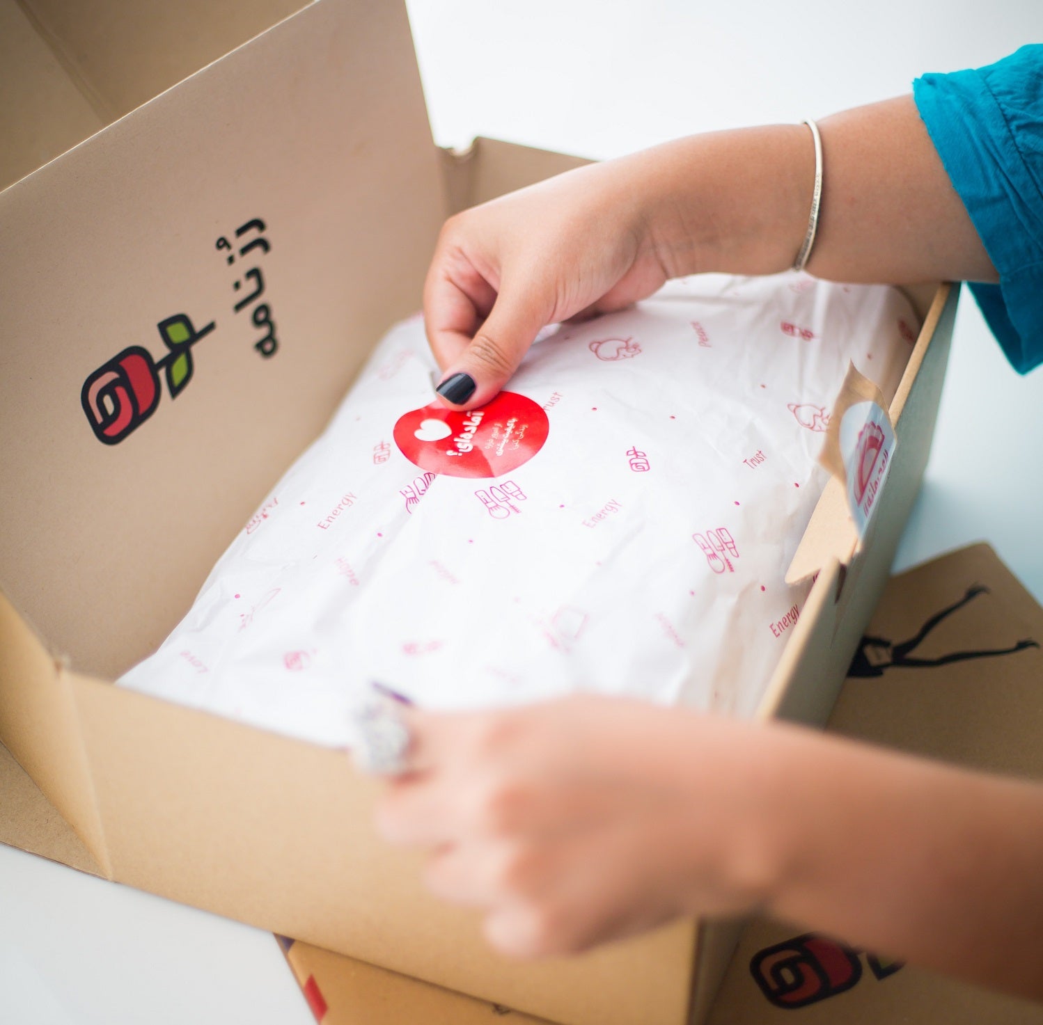 Das Foto zeigt eine Person, die ein Paket mit einem individuellen Aufkleber zuklebt. Auch für deine E-Commerce-Verpackung kann das eine tolle Lösung sein.