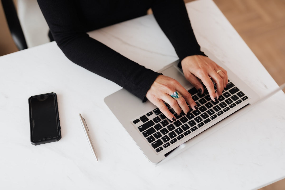 Eine Frau tippt auf der Tastatur ihres Laptops. Für die Eröffnung deines Shops lohnt sich ein Vergleich zwischen Ecwid vs. Shopify. 