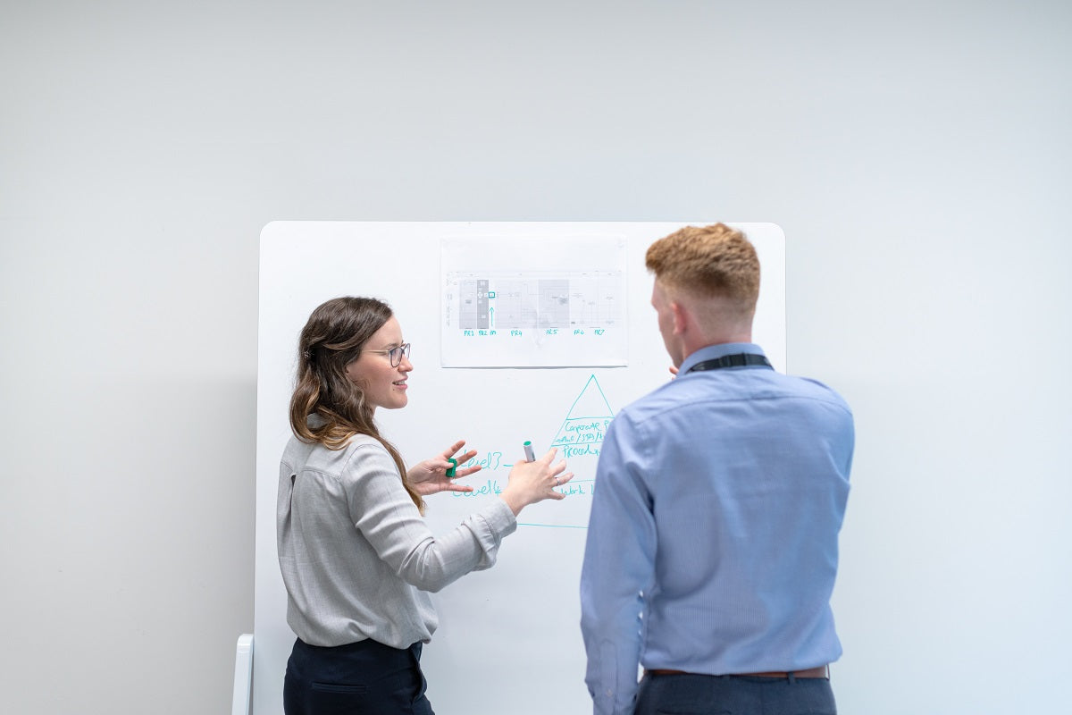 Zwei Personen unterhalten sich vor einem Whiteboard.