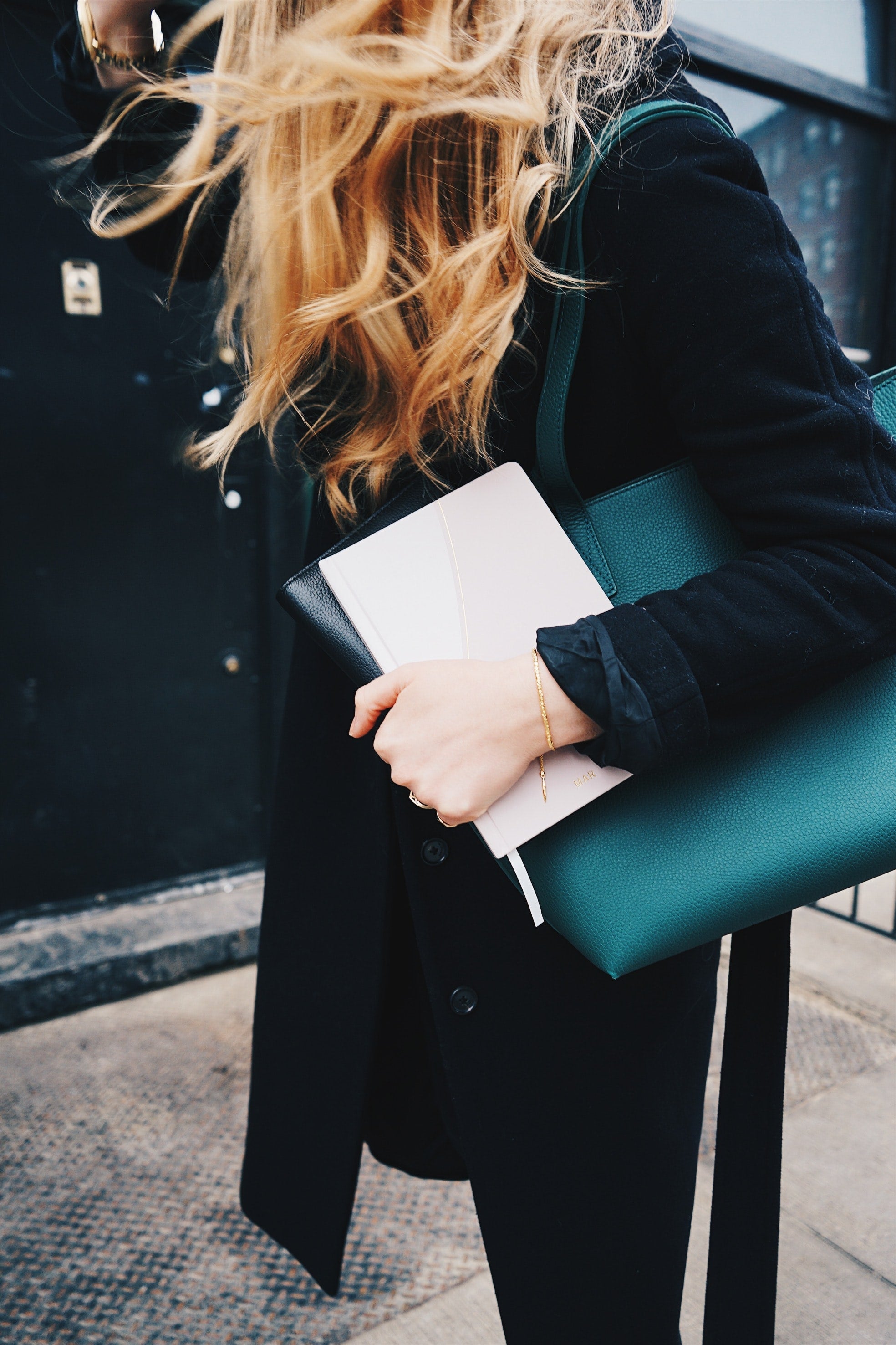 Eine Frau mit blonden Haaren in dunkler Kleidung mit Papieren und ihrem Executive Summary in der Hand