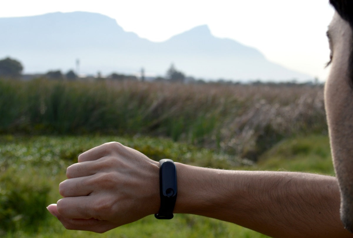 Das Bild zeigt den einen jungen Mann mit einem Fitness-Tracker am Handgelenk.