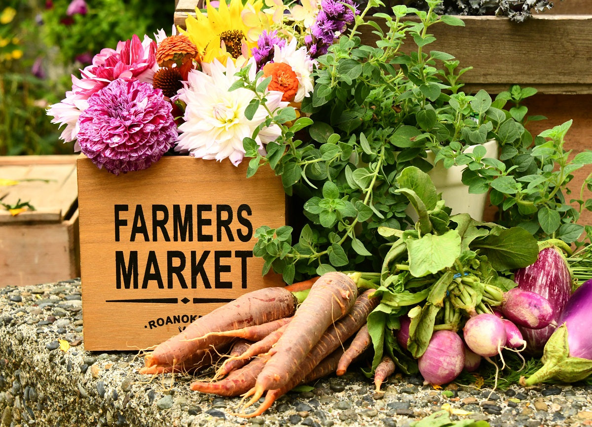 Auf dem Bild sind verschiedene Gemüsesorten zu erkennen, links davon steht ein hölzernes Schild mit der Aufschrift "Farmers Market". Das Bild steht sinnbildlich dafür, dass Landwirt:innen zu Gewerbetreibenden werden können, sobald sie ihre Waren selbst verkaufen.