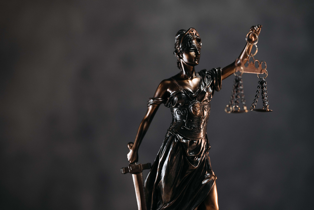 Eine Justicia-Statue vor dunklem Hintergrund als Symbolbild für die Rechte und Pflichten beim UG gründen