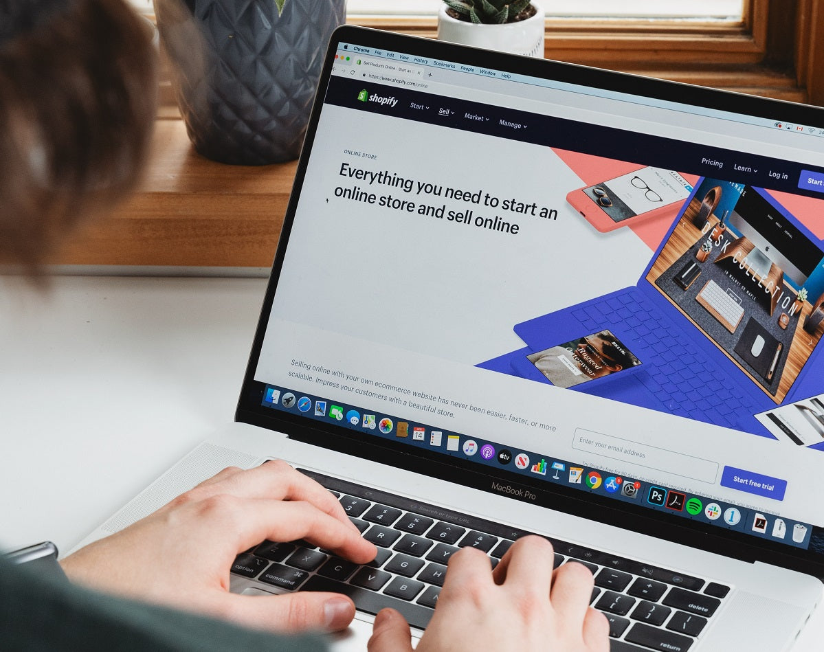 Das Foto zeigt einen Laptop, auf dem die Homepage von Shopify geöffnet ist, einem Homepage-Baukasten für Onlineshops.