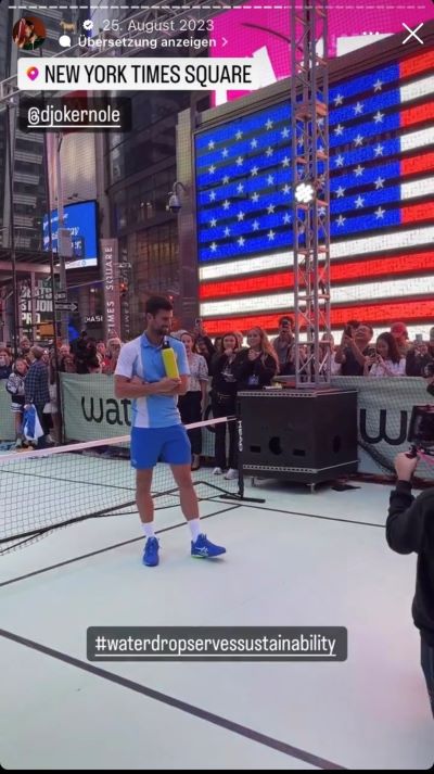 Der Tennisspieler steht am NewYork Times Square mit einer Wasserflasche.