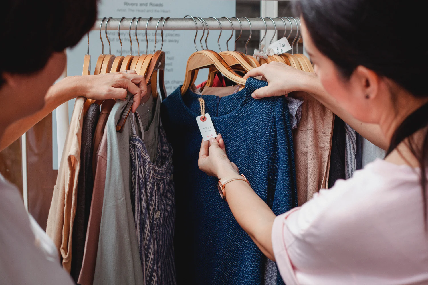 Das Foto zeigt zwei Personen, die sich den Preis eines Pullovers an einer Kleiderstange anschauen. Die Inflation beeinflusst die Konsumtrends in diesem Jahr besonders stark.