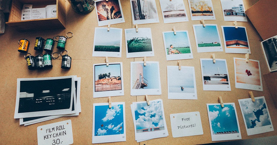 Ein Tisch mit vielen Polaroid Bildern und Filmrollen und dem Zettel "kostenlose Bilder"