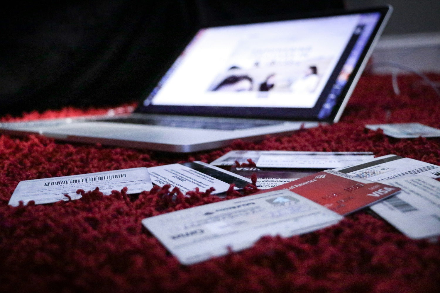 Das Foto zeigt einen aufgeklappten Laptop um den verschiedene Kreditkarten verteilt liegen.