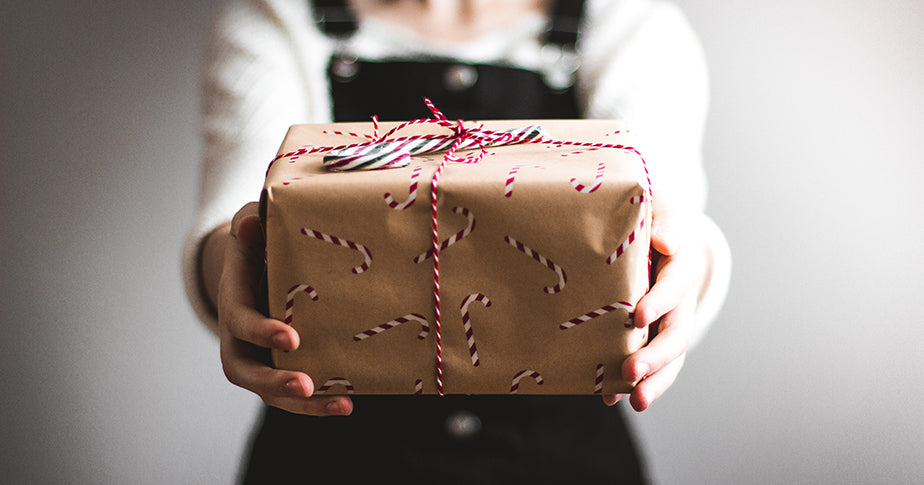 Jemand übergibt ein Weihnachtsgeschenk als Beispiel für eine Geschenkeaktion bei der Kundenbetreuung zu Weihnachten