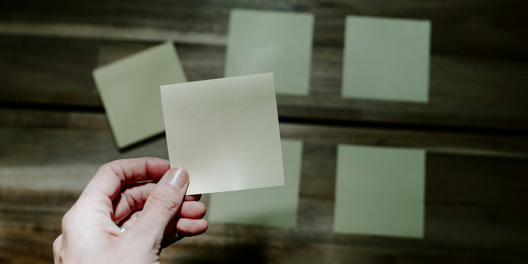 Das Foto zeigt einen Tisch auf dem Post-its sortiert abgelegt sind. Eine Hand legt gerade ein weiteres Post-it dazu. Bei der Kundensegmentierung geht es ebenfalls darum, deine Kundschaft nach konkreten Merkmalen zu sortieren.