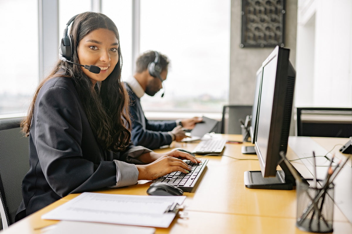 Eine Frau, die im Kundenservice arbeitet, sitzt an ihrem Computer und trägt ein Headset.