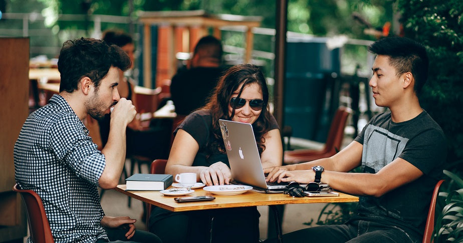 Eine Gruppe junger Menschen sitzt zusammen an einem Tisch. Was die Millennials ausmacht, erfährst du im Beitrag.