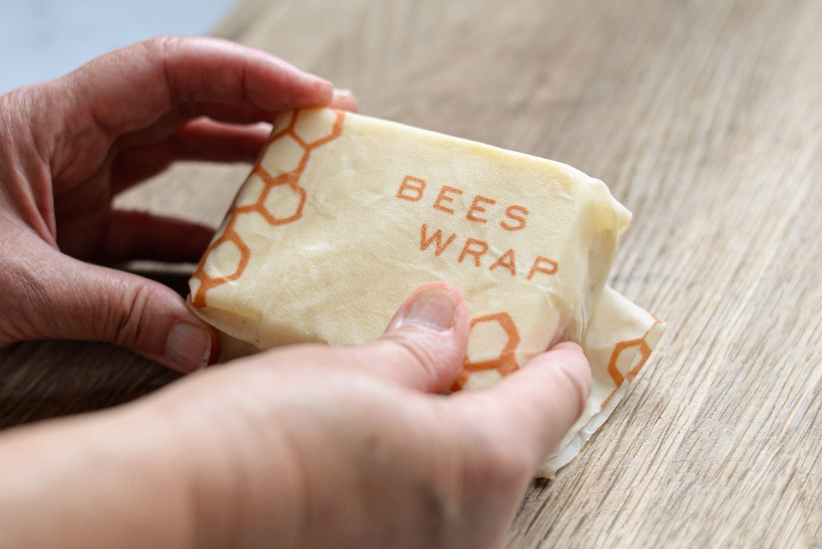 Das Foto zeigt zwei Hände, die gerade ein Brot in einem Bienenwachstuch einpacken. Mehr nachhaltige Produkte Ideen findest du im Beitrag.