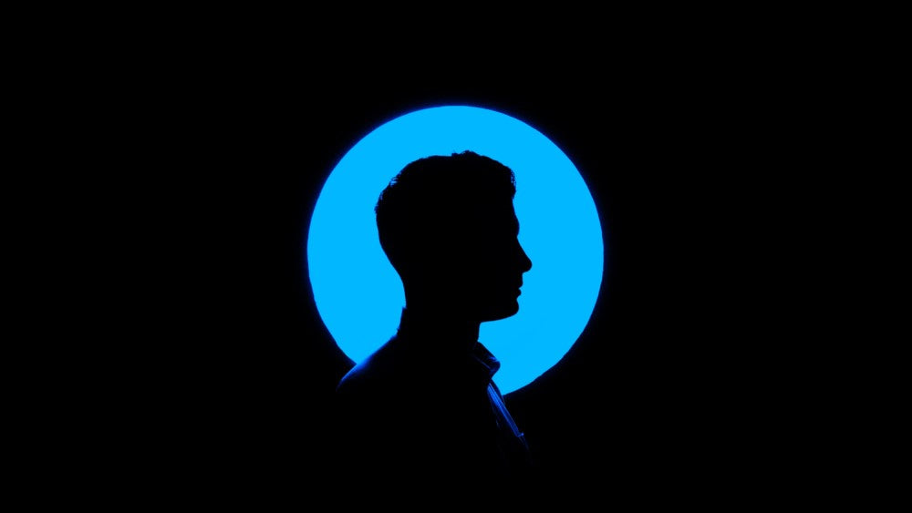 Schatten einer männlichen Person vor Schwarzer Leinwand mit blauem Punkt