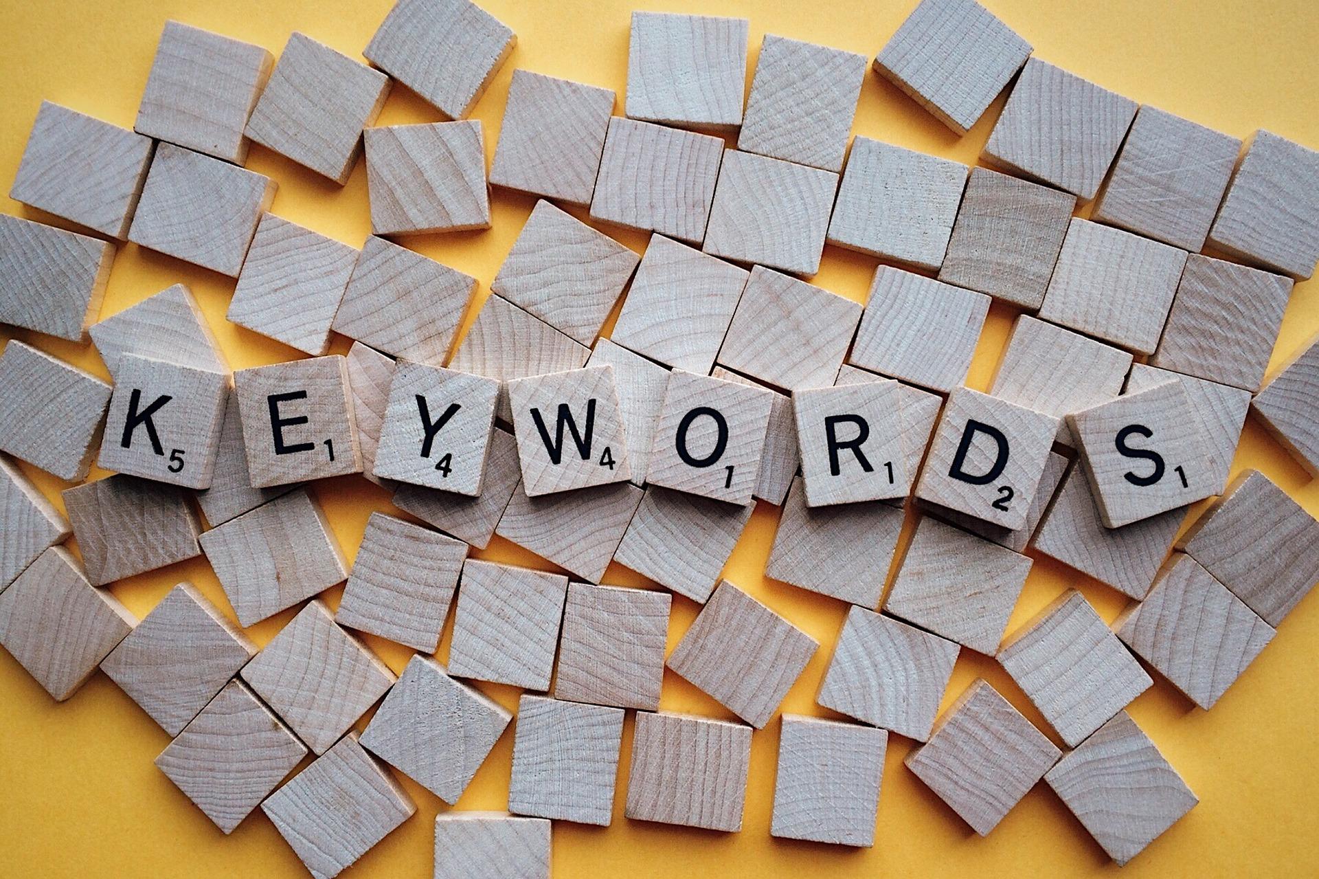 Das Wort "Keywords" ist mit einzelnen Buchstaben-Steinen eines Spiels zusammengesetzt. Das Wort liegt auf mehreren anderen umgedrehten Spielsteinen auf einem orangefarbenem Untergrund. Mit den richtigen Keywords wird SEO für deinen Onlineshop zum Klacks.