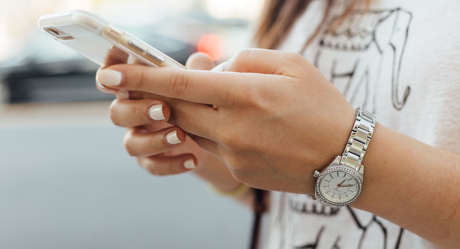 Eine Person mit einer Armbanduhr am Handgelenk hält ein Handy in beiden Händen und sucht in Verschiedenen Verzeichnissen nach eine SEO optimierten Website