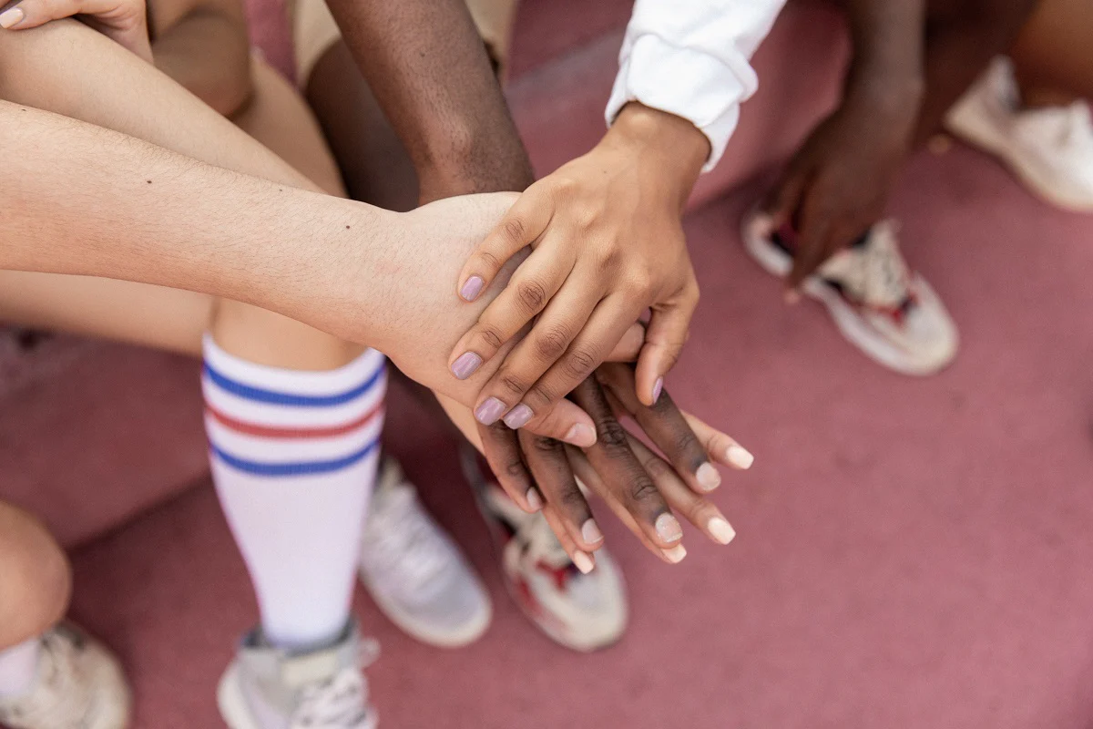 Das Foto zeigt Menschen, die ihre Hände aufeinander legen. Es symbolisiert die Bindung, die du mit deiner Kundschaft aufbauen kannst, wenn du Social Selling betreibst.