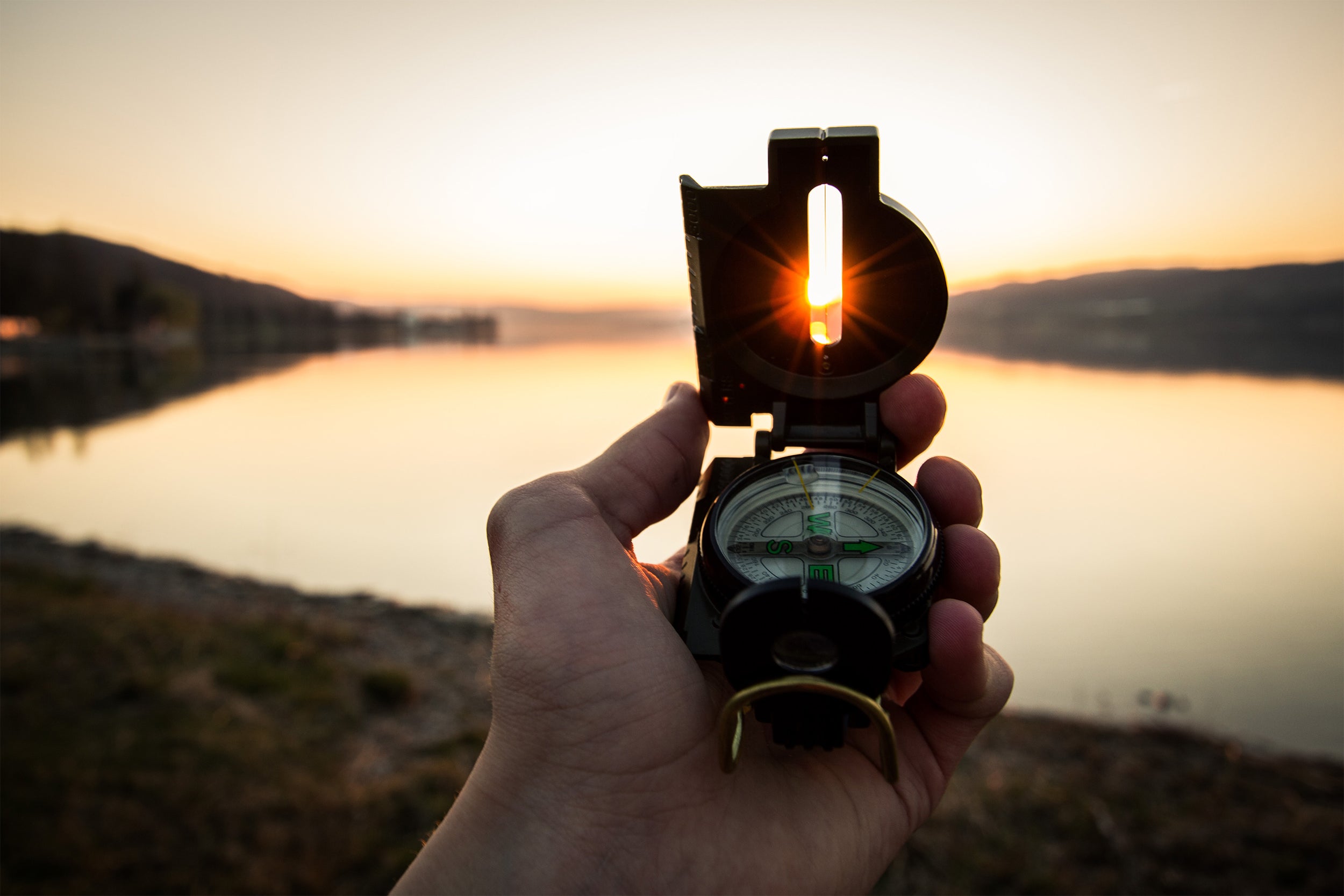 Eine Hand, die einen Kampass hält vor einer Sonnenuntergangskulisse als Symbol für die Zukunft der Warenwirtschaftssysteme