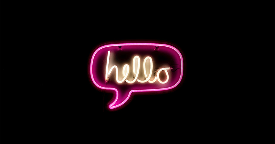 Ein schwarzes Bild mit der Neon-Leuchtschrift "Hello" als Zeichen für die "Über Uns"-Seite