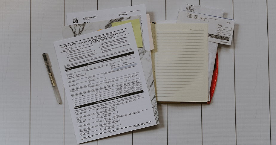 Ein Formular für eine Umsatzsteuervoranmeldung liegt ausgebreitet auf einem weißen Holztisch.