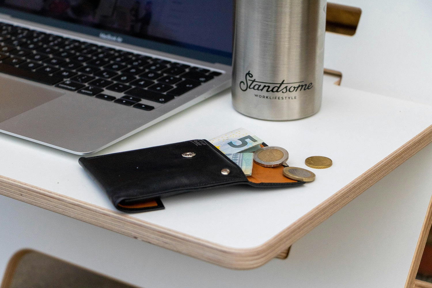 Das Foto zeigt einen Schreibtisch, auf dem ein Portemonnaie liegt, aus dem Geld herausschaut. Wir geben dir wertvolle Tipps zur Unternehmensfinanzierung im Beitrag.