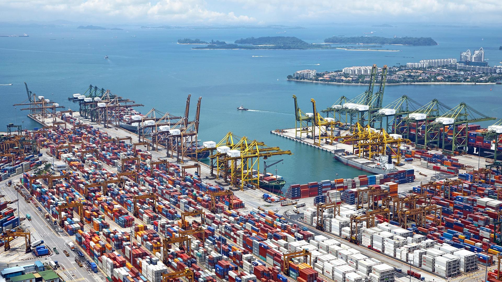 Blick auf einen riesigen Containerhafen am Wasser. In der Ferne sind einzelne Inseln zu erkennen. Die passenden Versandoptionen sind entscheidend, wenn du weltweit verkaufen willst.