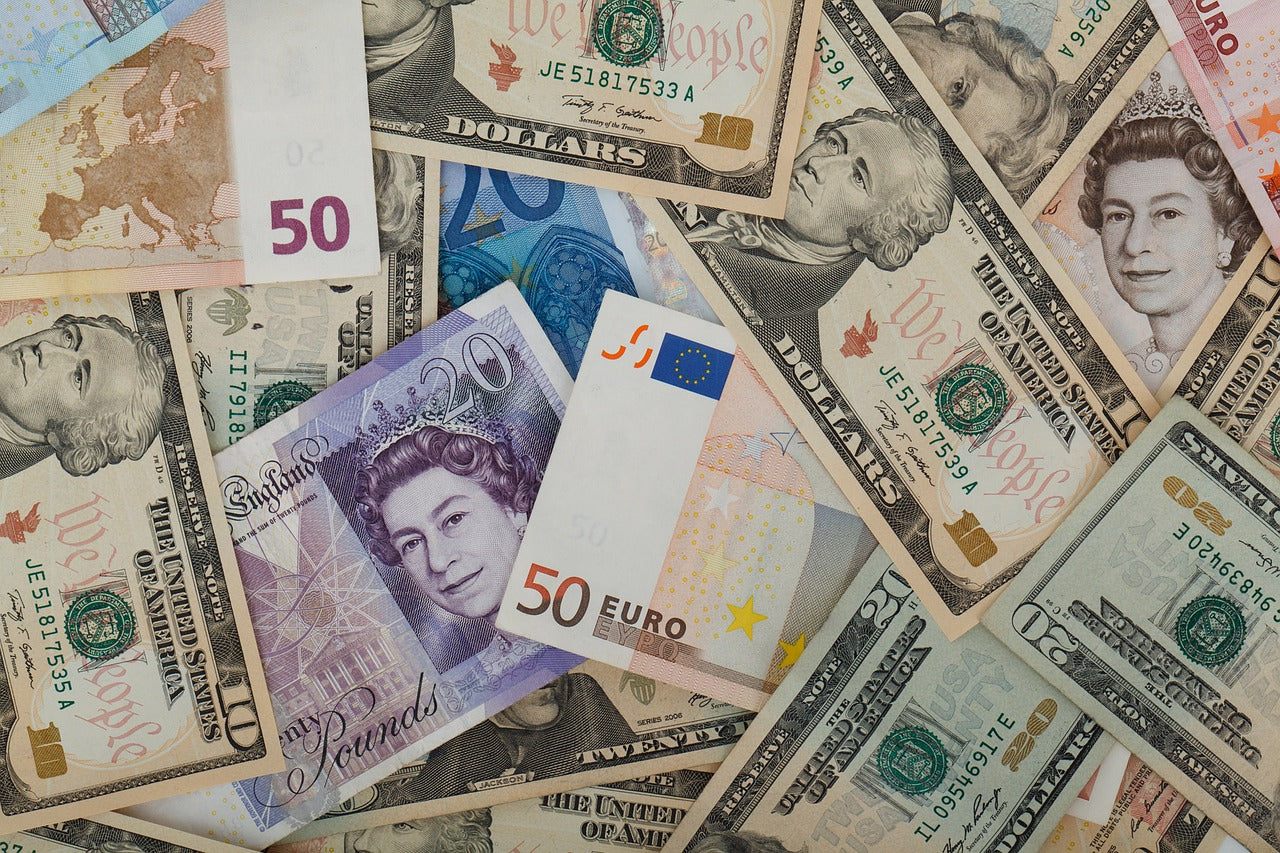 Nahaufnahme von unterschiedlichen Geldscheinen, darunter Euro, Pfund und Dollar. Weltweit verkaufen geht am besten, wenn du die jeweilige Landeswährung in deinen Shop einbindest.
